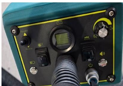 Close-up of a green industrial testing device with control knobs, gauges, and tubing (no visible text or symbols)