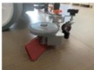 Close-up of a mechanical device with a red base and circular top, no visible text or symbols
