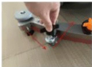 Close-up of a hand using a small black tool to adjust a small component on a wooden surface, with no visible text or symbols.