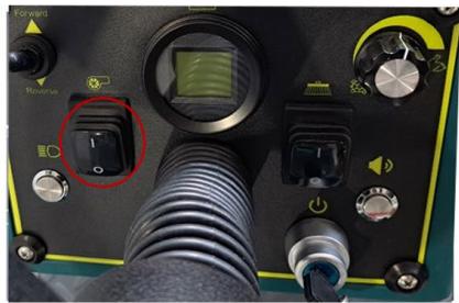 Close-up of a black electronic device control panel with buttons, dials, and a highlighted rotary knob (no readable text or symbols)