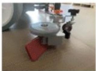 Close-up of a mechanical device with a red base and circular top, no visible text or symbols
