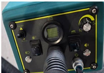 Close-up of a green industrial testing device with control knobs, gauges, and tubing (no visible text or symbols)