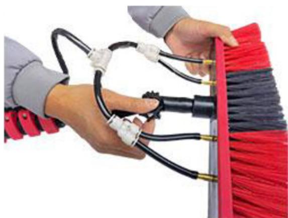 Close-up of hands cleaning a red broom with black and white cables (no text or symbols visible)