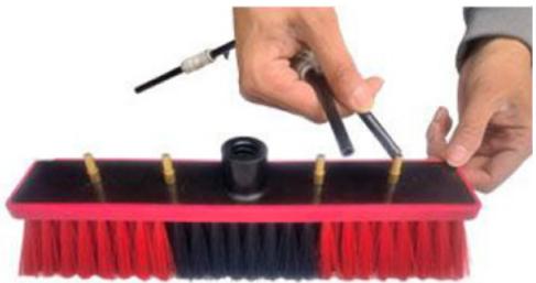 Close-up of hands using a screwdriver to clean or store items on a red broom (no text or symbols visible)
