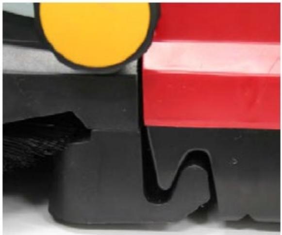 Close-up of a mechanical component with black base, yellow circular top, and red stripe (no text or symbols visible)