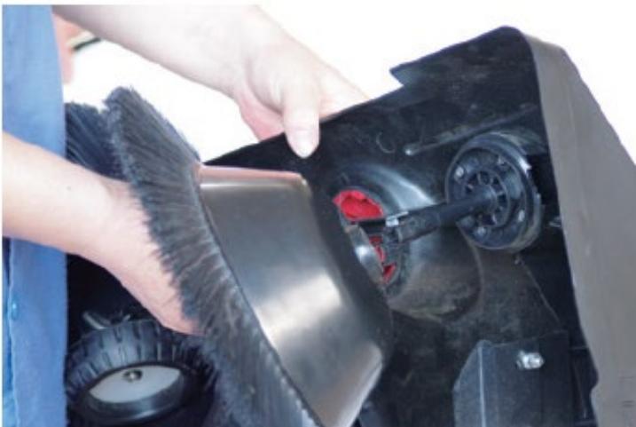 Close-up of a person cleaning or adjusting a mechanical component with a brush (no visible text or symbols)