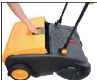 Hand operating a yellow and black manual sweeper with a handle (no text or symbols visible)