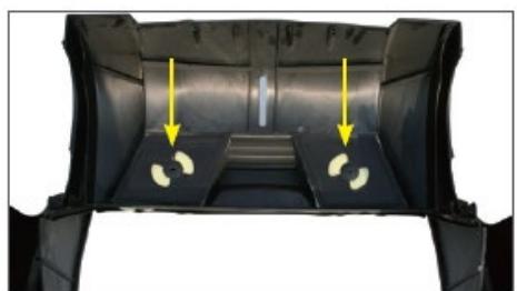Interior view of a car cab with two yellow arrows pointing to small white objects on the tray (no text or symbols visible)