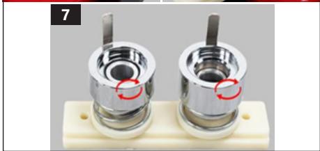Close-up of two metallic cylindrical mechanical components mounted on a white base plate (no text or symbols visible)