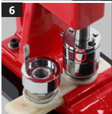 Close-up of a red mechanical device with metallic components and a circular mark on the base (no visible text or symbols)