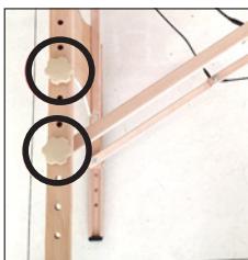 Close-up of a wooden bracket with two circular cutouts on one end (no text or symbols visible)