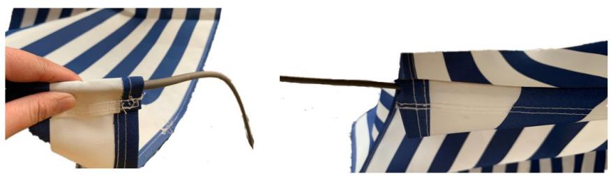 Close-up of a hand holding a white cable with a string, next to a close-up of a striped awning (no text or symbols visible)