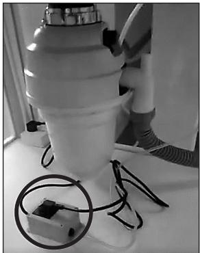 Black-and-white photo of a spray gun with attached wires and a small electronic device (no visible text or symbols)