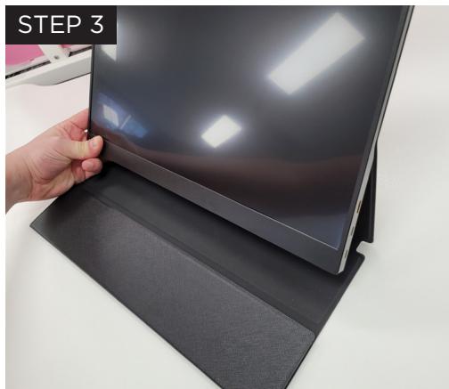 Close-up of a hand adjusting a black electronic device with a flat screen (no visible text or symbols)
