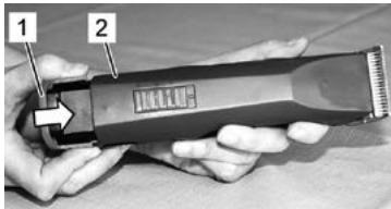 Black-and-white photo of hands using a hairbrush with labeled parts 1 and 2, showing a graphic symbol on the brush.