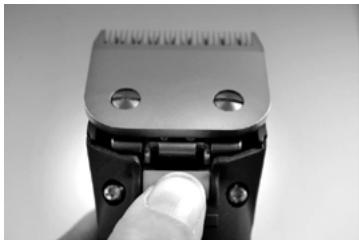 Close-up of a mechanical component with a finger inserted, showing mounting holes and a handle (no text or symbols visible)