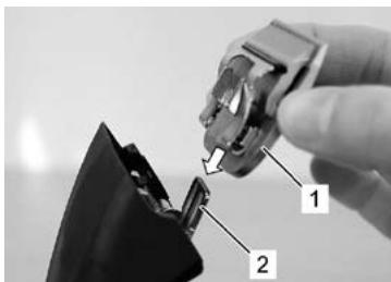 Close-up of a hand holding a small electronic device with labeled parts (1 and 2), no visible text or symbols on the device itself.