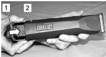 Photo of a hand holding a hairbrush with labeled parts 1 and 2, showing a brand mark.